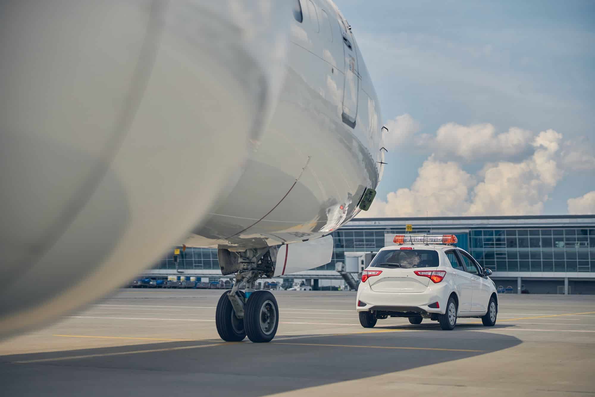 Coche de servicio frente a un avión en pista